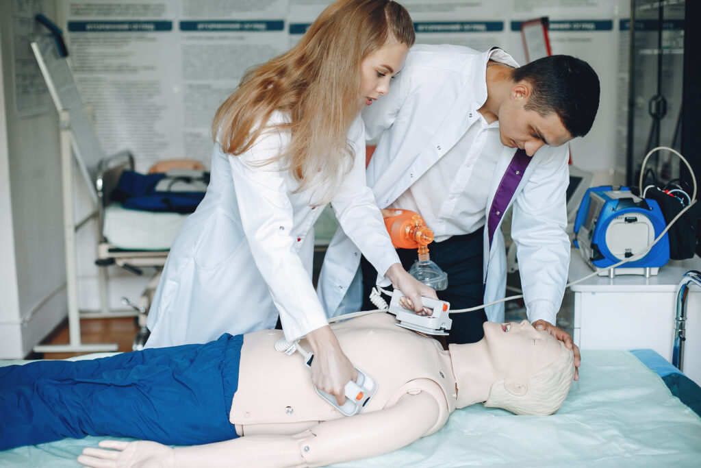 Healthcare professionals performing defibrillation and resuscitation training during structured clinical training.
