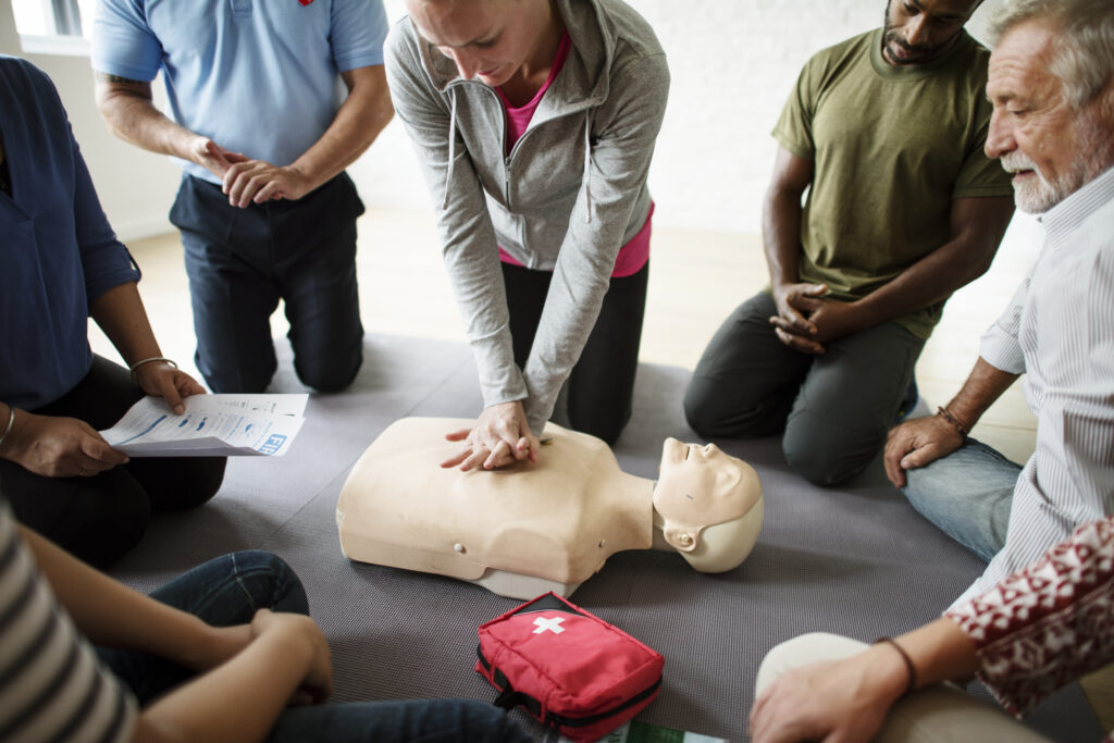 Healthcare professionals performing CPR on a training manikin during structured clinical training for emergency response.